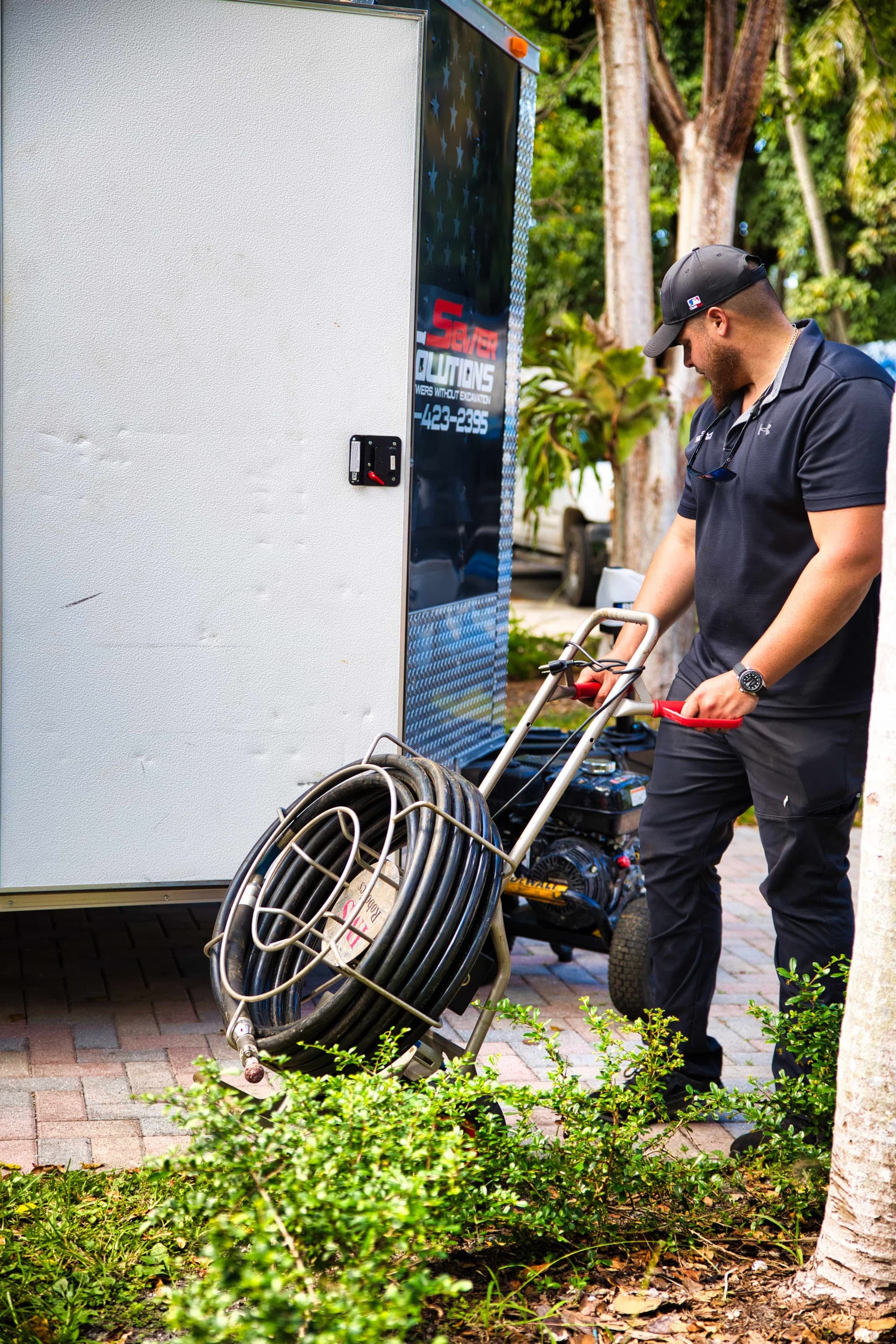 An Aqua Pro technician wheeling a sewer camera reel past the company trailer