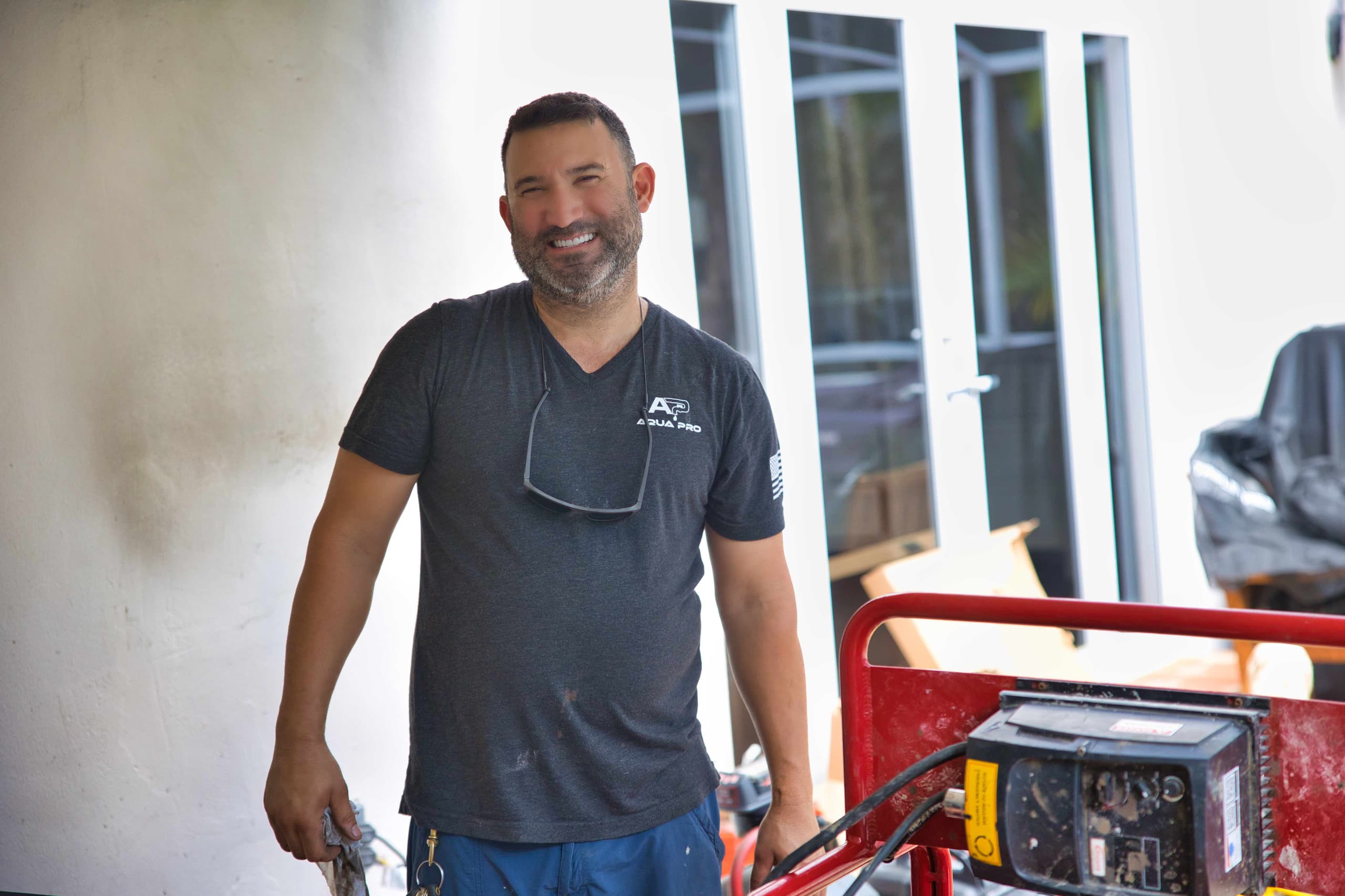 Smiling Aqua Pro technician in a company shirt next to sewer equipment