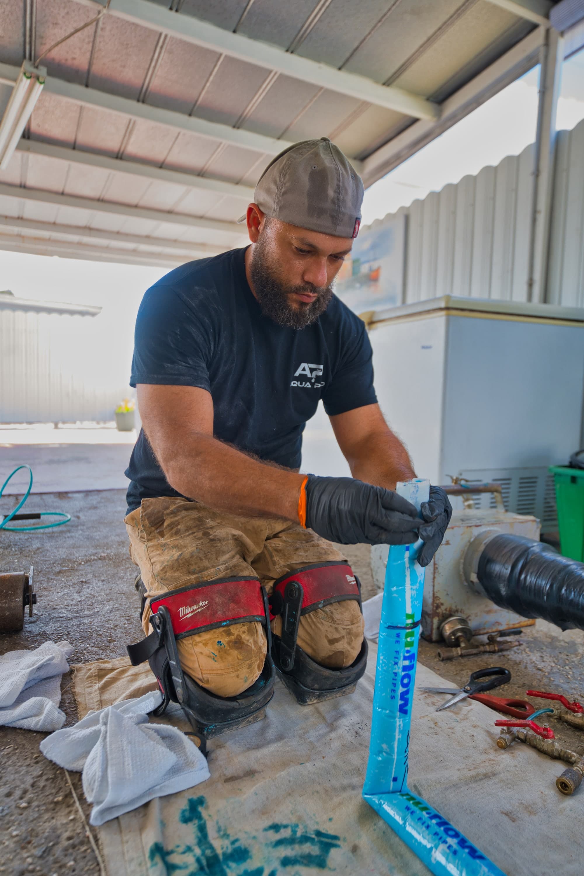 An Aqua Pro technician preparing a blue pipe liner before installation