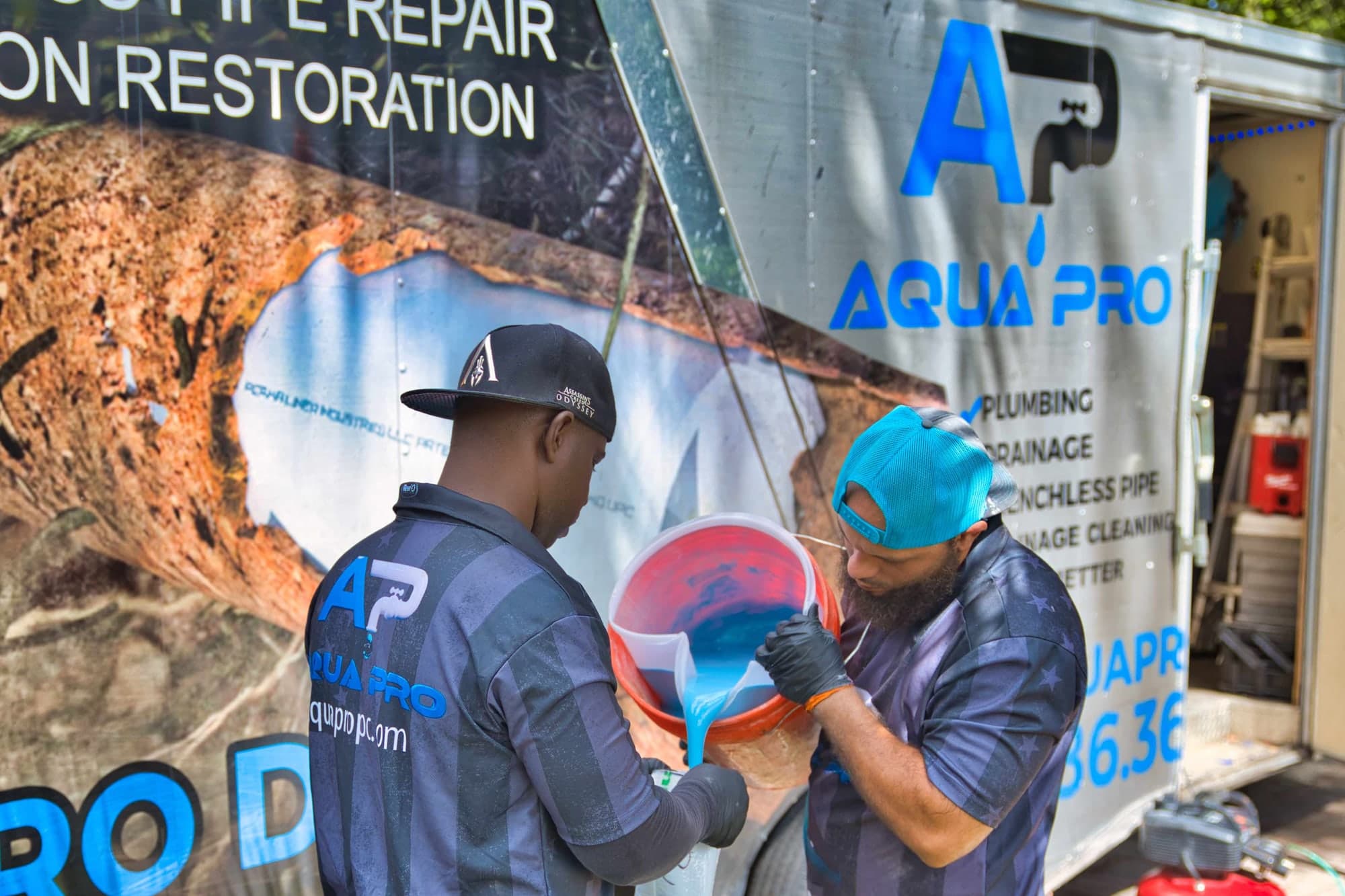 Two Aqua Pro technicians mixing liner resin beside the company trailer