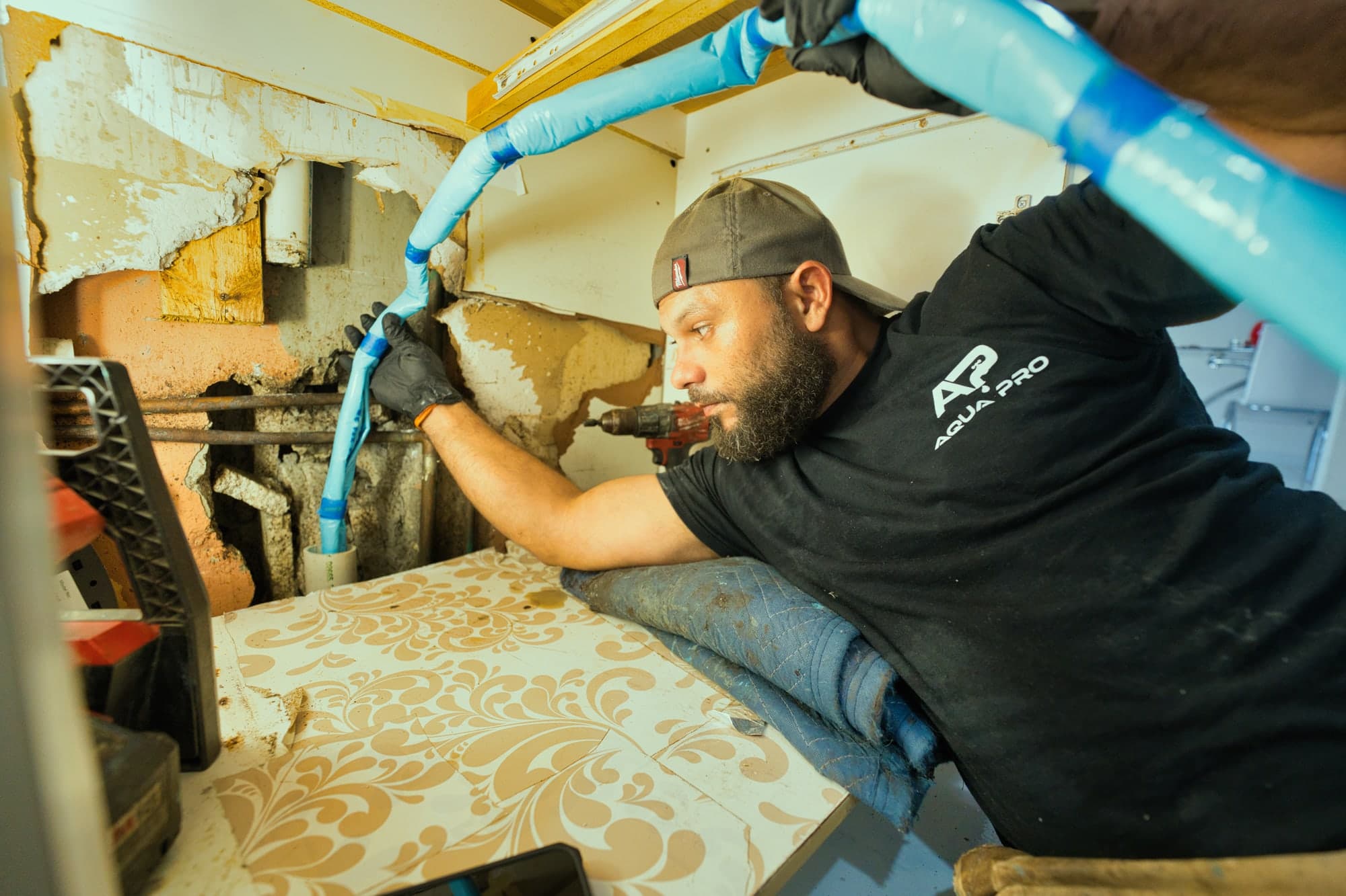 An Aqua Pro technician working at an opened wall access to a drain line