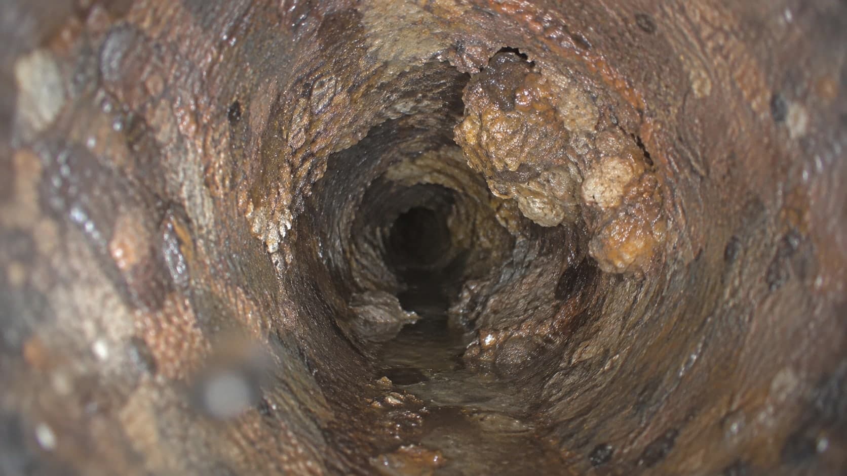 Illustration: camera view of rust scale narrowing a cast iron pipe