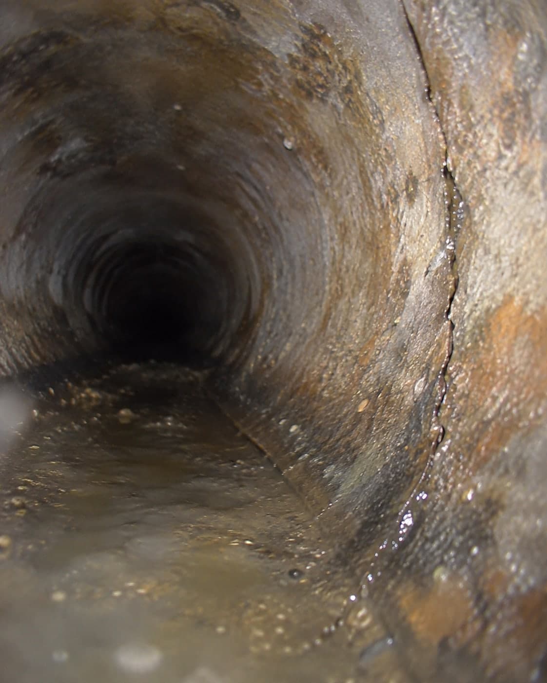 Rendered camera view of a long crack running along the bottom of a sewer pipe