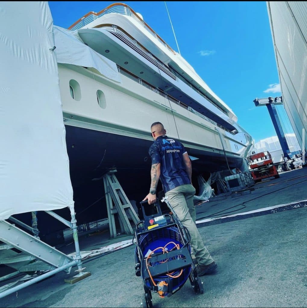 An Aqua Pro technician with equipment beside a yacht