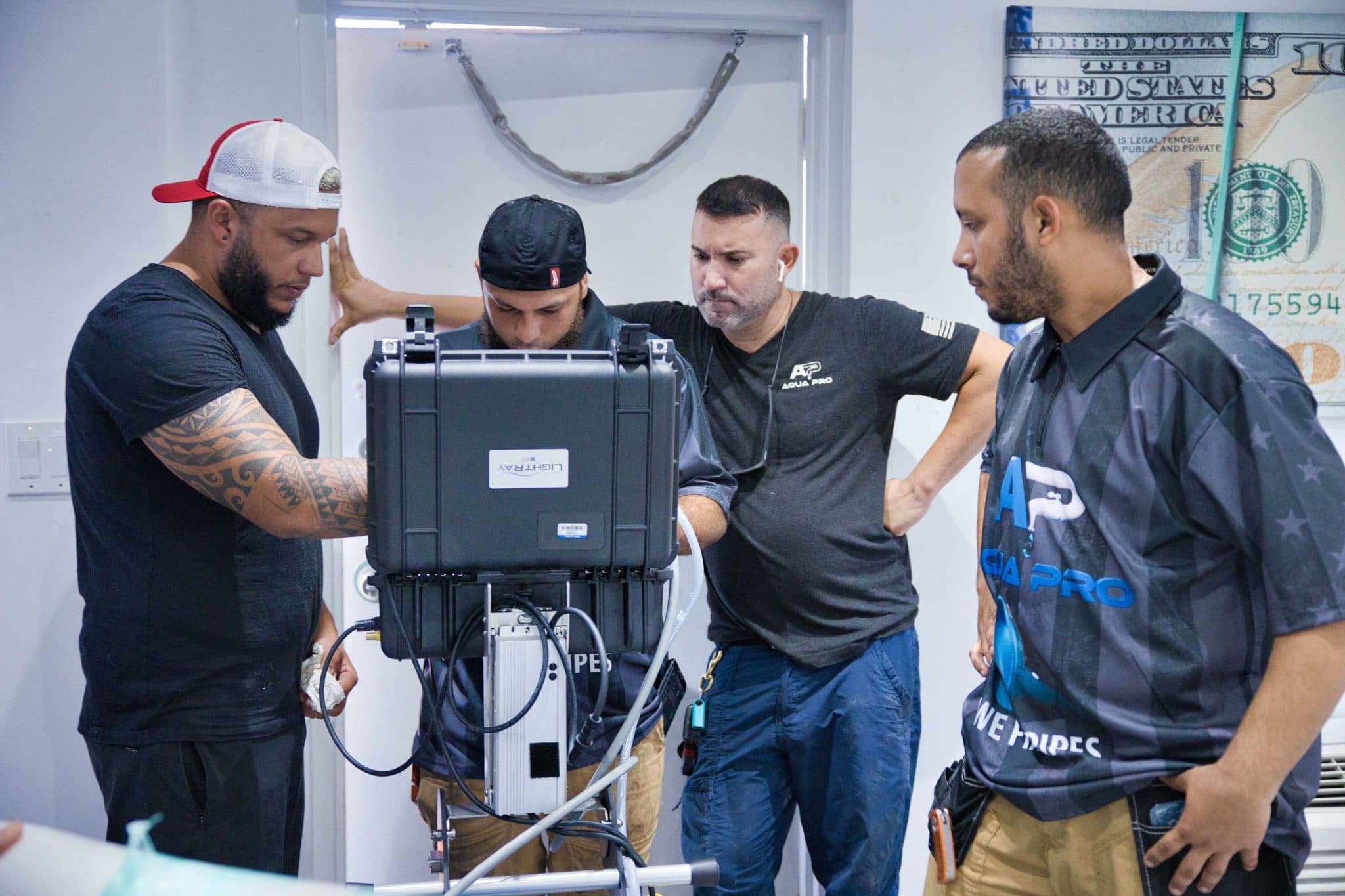 Four Aqua Pro team members gathered around a LightRay UV curing controller in the company lab