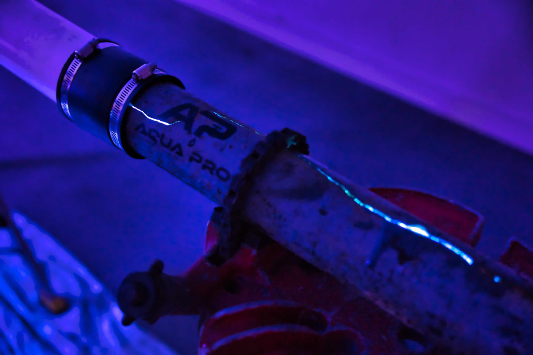 UV light glowing through the joint of a test pipe during a LightRay cure in the Aqua Pro lab