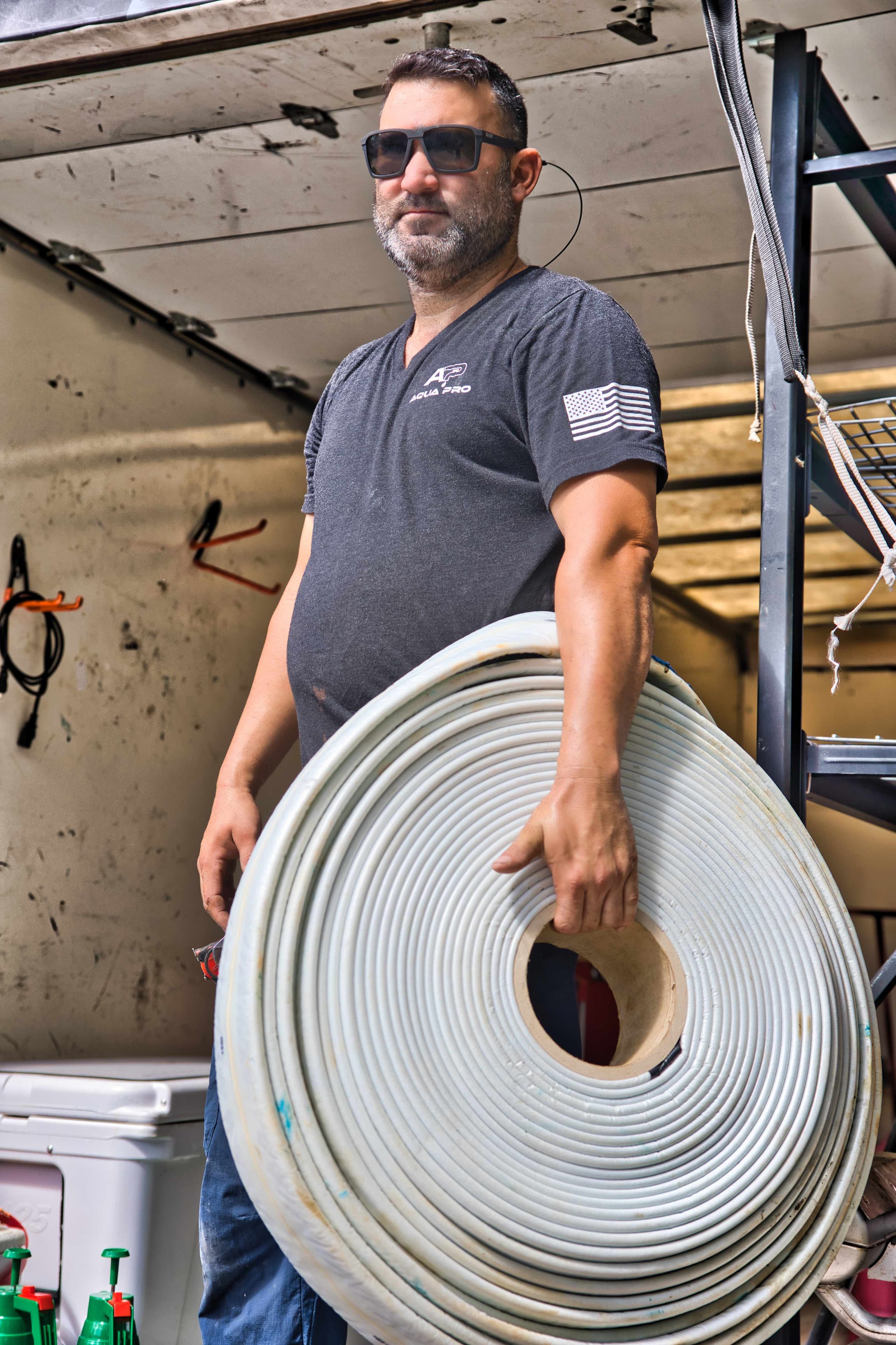Technician carrying a roll of pipe liner from the work trailer