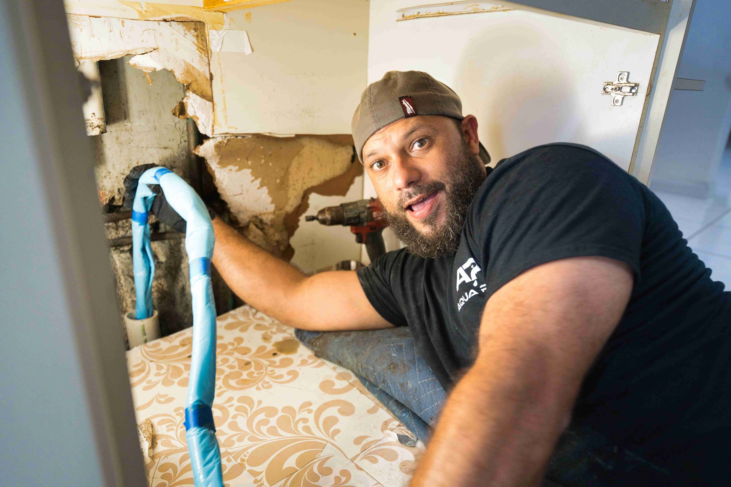 An Aqua Pro plumber working under a sink